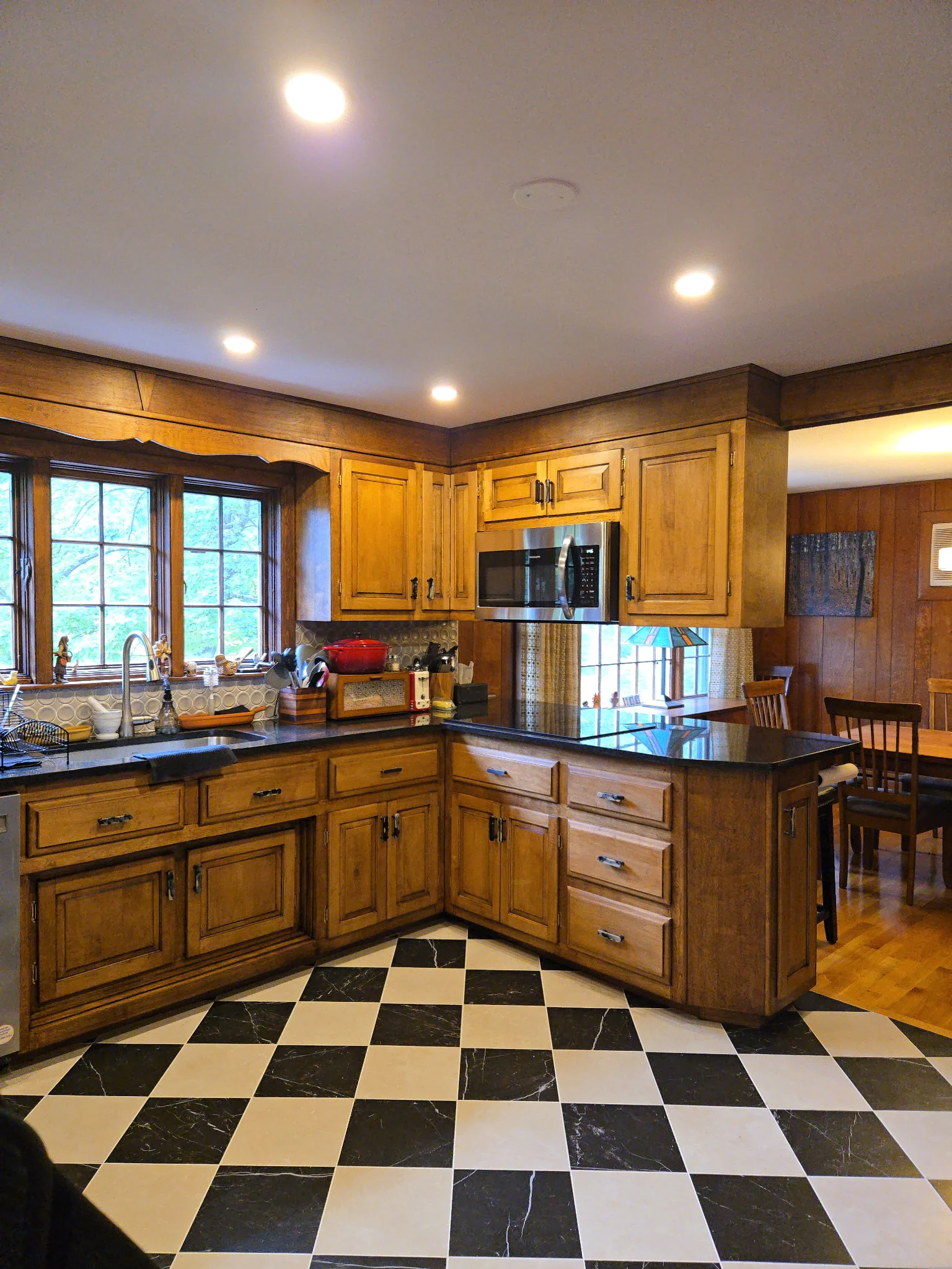 Elegant kitchen with wood cabinetry, black granite counters, and marble diamond floor pattern — Custom Cabinet Installation by Innovative Build Solutions.