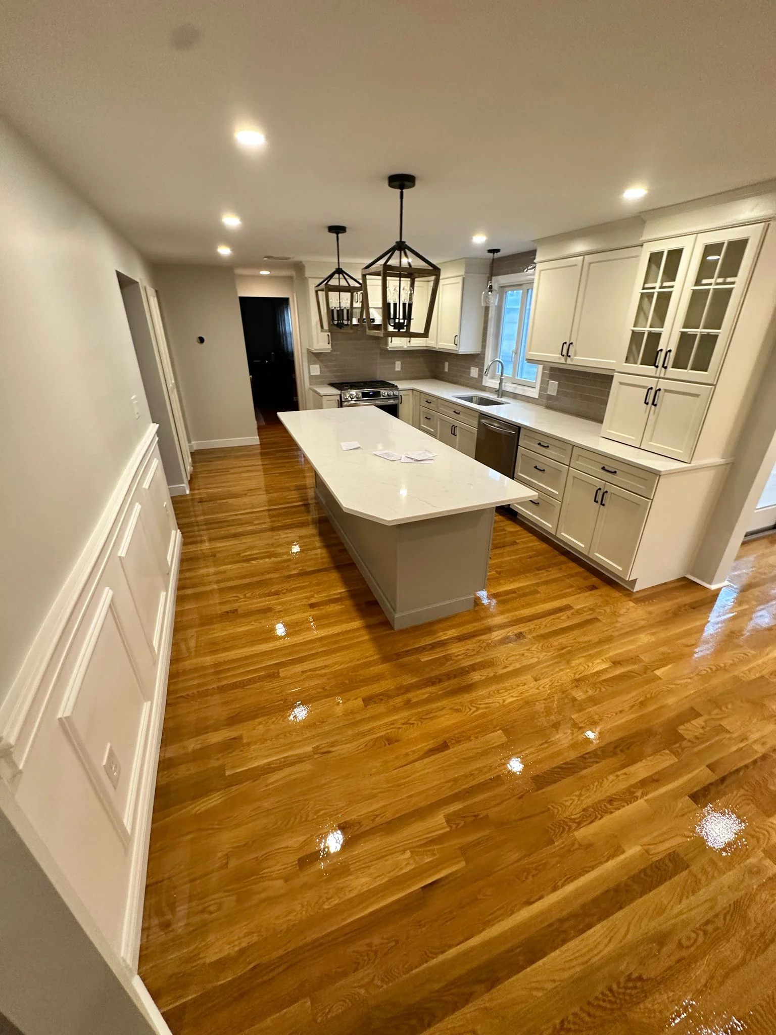Modern kitchen renovation with cream cabinetry, white island, hardwood floors, and pendant lighting by Innovative Build Solutions.
