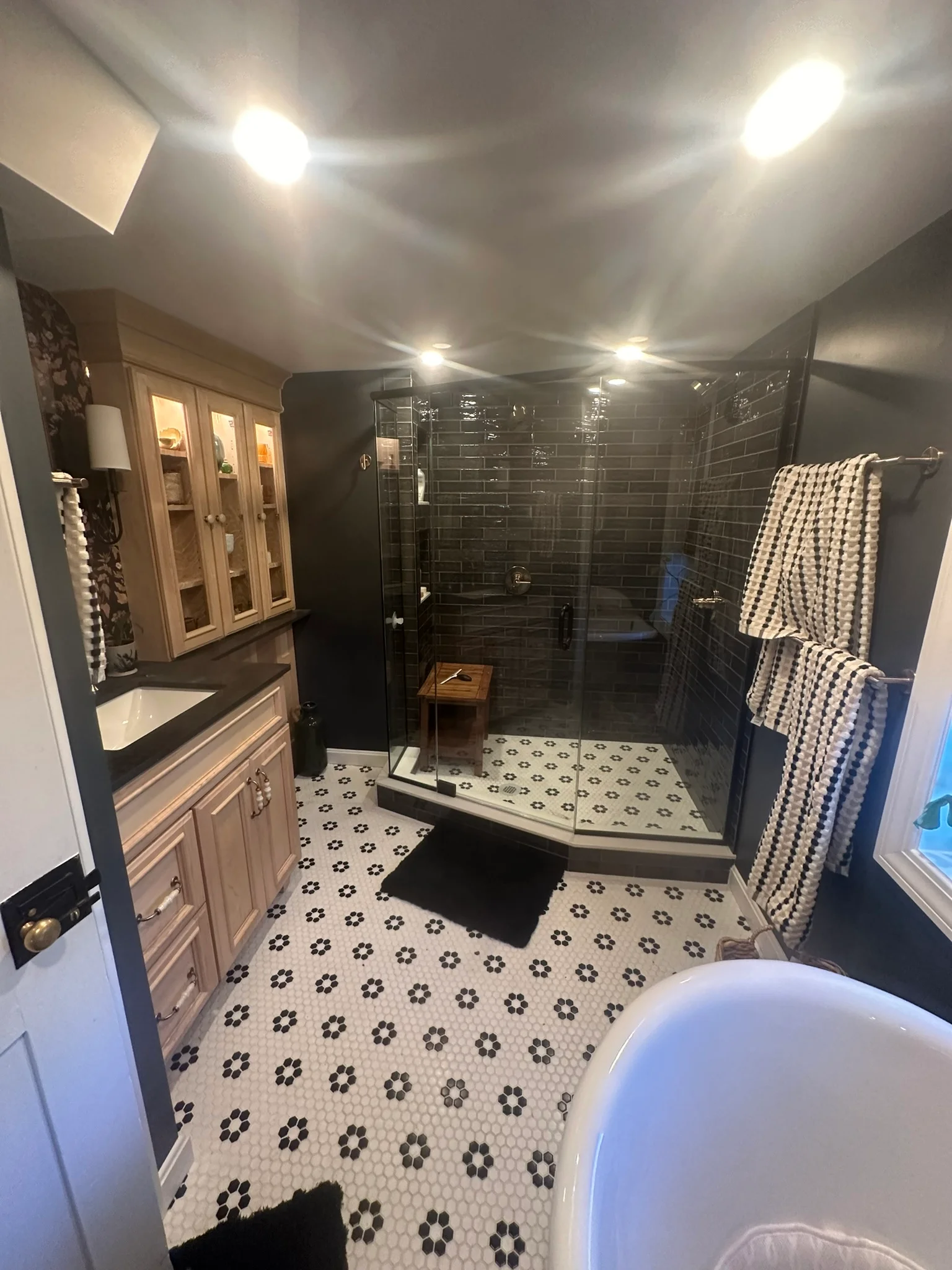Modern master bathroom remodel with black subway tile shower, patterned hexagon floor, and light wood vanity by Innovative Build Solutions.