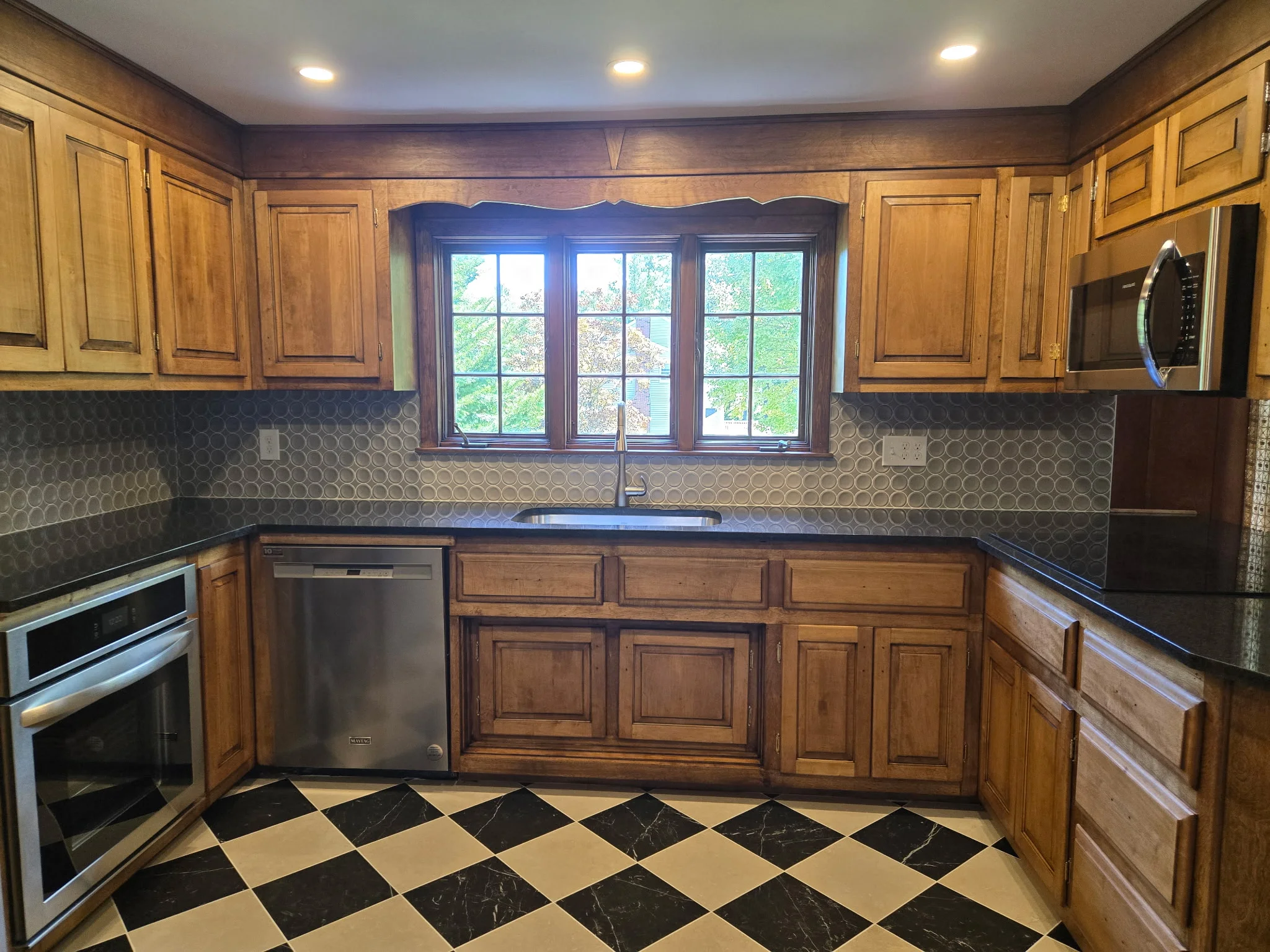 Kitchen with wood cabinetry, granite counters, hexagon backsplash, and diamond tile floor — Remodeling Consultation by Innovative Build Solutions.